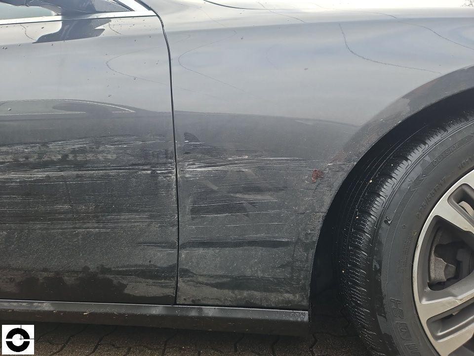 Seitliche Ansicht linke Fahrzeugseite mit deutlichen Schleifspuren und Kratzern an Tür und Kotflügel