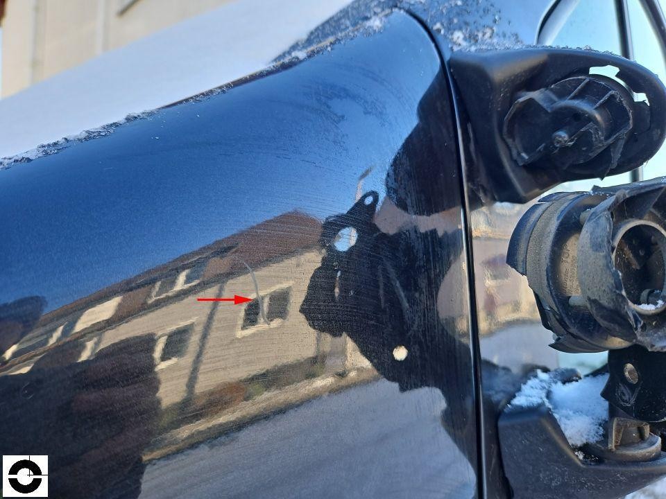 Detailaufnahme hinterer Kotflügel rechts mit Kratzern und Lackschäden, roter Pfeil markiert Schadstelle