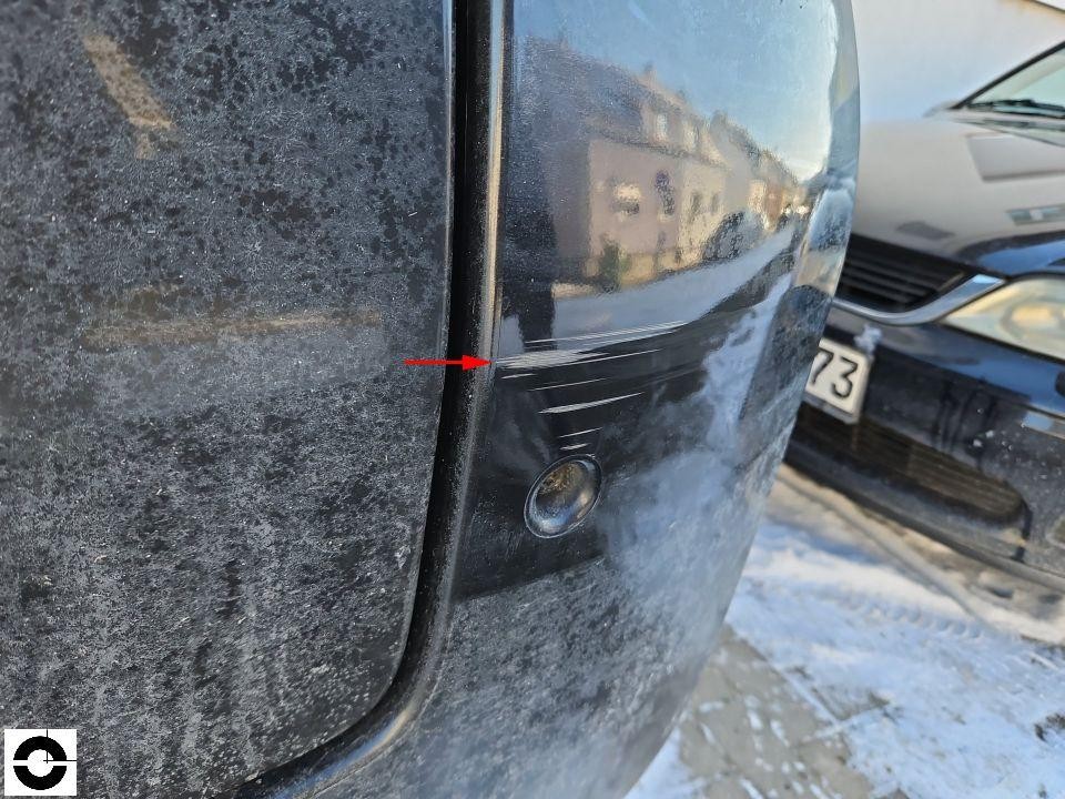 Hintere Stoßstange rechts mit Kratzern, roter Pfeil markiert Schaden, Einparksensor sichtbar