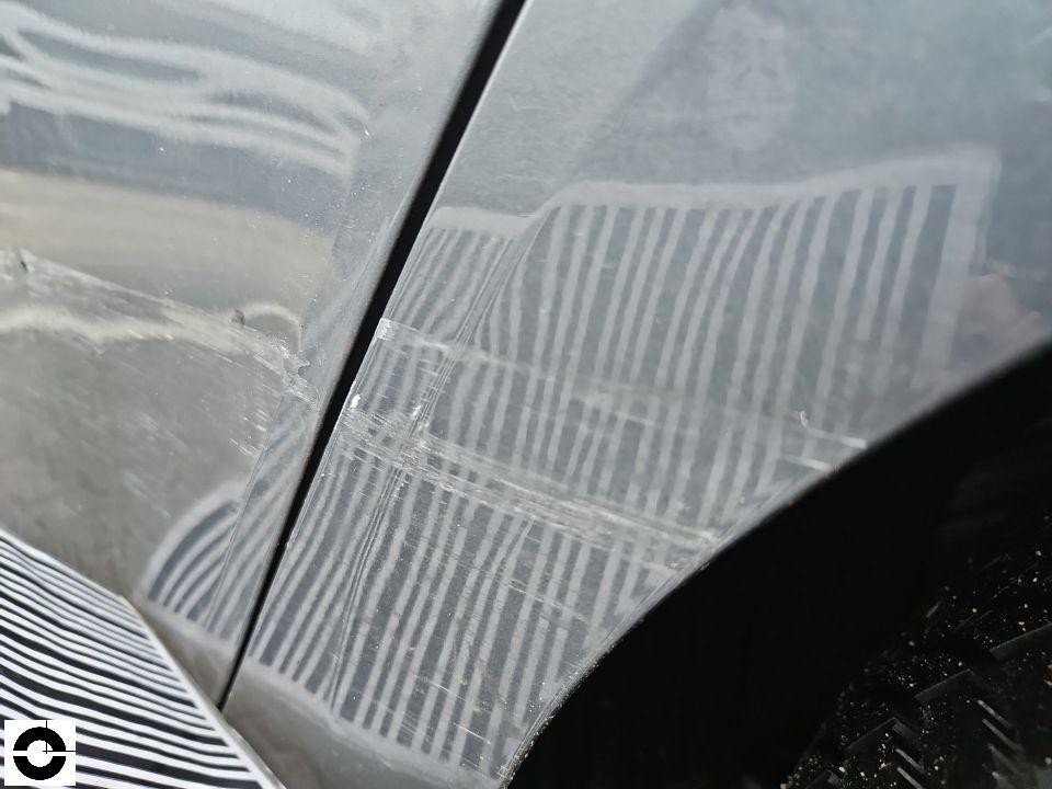 Detailaufnahme Kratzer und Schleifspuren auf dunkler Lackoberfläche, vermutlich Kotflügel oder Tür