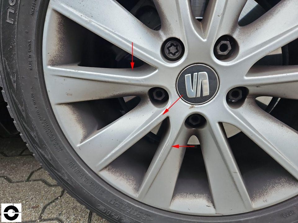 Nahaufnahme Alufelge mit roten Markierungspfeilen auf Beschädigungen/Kratzer