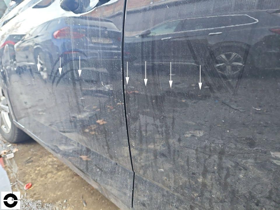 Linke Fahrzeugseite mit Kratzern an hinterer Tür und Kotflügel, Pfeile markieren Schäden