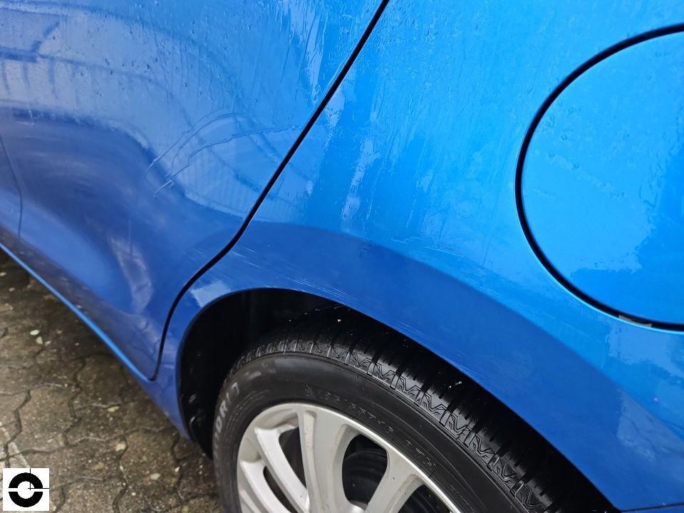 Hinterer linker Kotflügel mit Kratzern, Tankdeckel sichtbar, blaue Lackierung