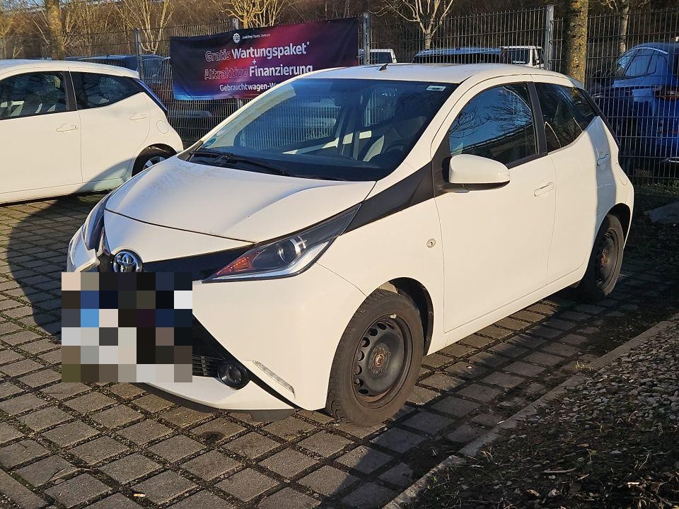 Frontansicht schräg rechts, weißer Kleinwagen auf Parkplatz, Kennzeichen pixeliert