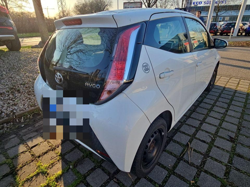 Heckansicht schräg rechts, weißer Kleinwagen, Kennzeichen bereits pixeliert, Parkplatz