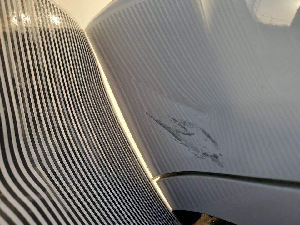 Motorhaube mit Lackschaden und Abriebspuren unter Streifenlicht-Beleuchtung