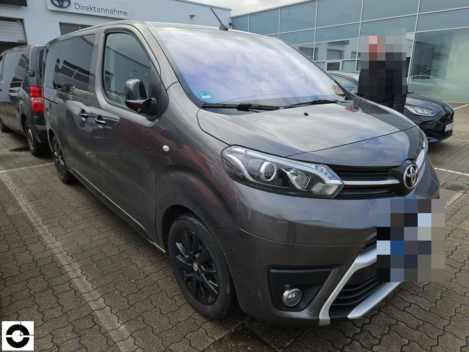 Frontansicht schräg rechts, dunkelgrauer Transporter vor Toyota-Autohaus, keine sichtbaren Schäden