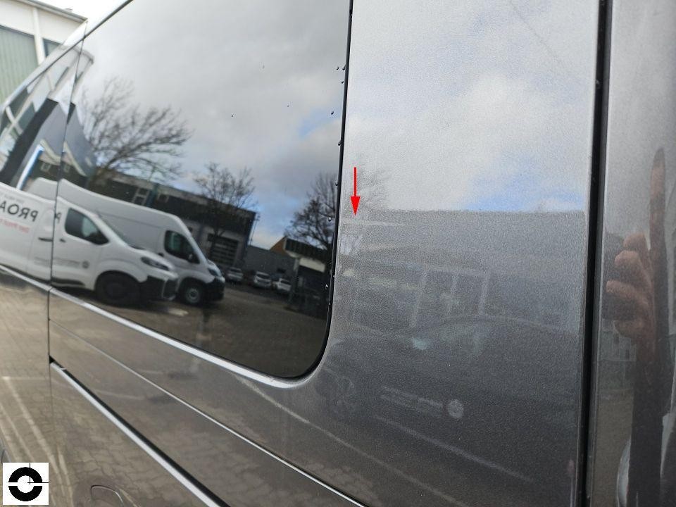 Hintere Seitenscheibe rechts mit rotem Pfeil auf Schadensbereich, Spiegelung zeigt Umgebung