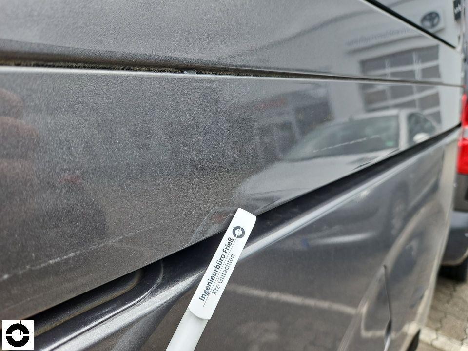 Nahaufnahme der linken Fahrzeugseite mit Zierleiste und Messstab des Gutachters