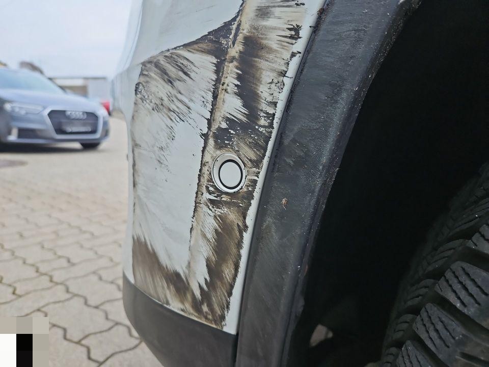 Hintere Stoßstange links, starke Schürfspuren und schwarzer Abrieb, Parksensor sichtbar