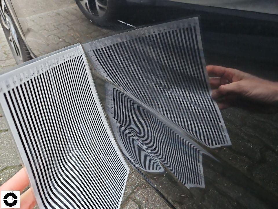 Dellenprüfung mit Streifenlineal an dunkler Motorhaube, Verformungen sichtbar