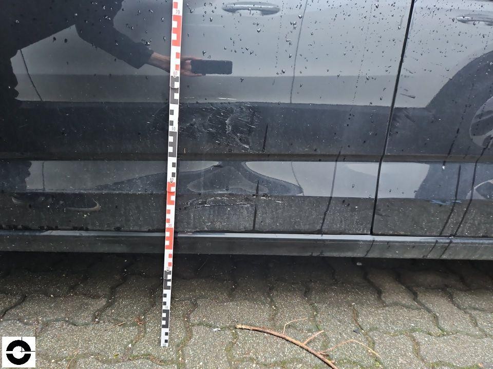 Seitenansicht linke Fahrzeugseite mit Kratzern und Lackschäden, Messlatte zur Dokumentation