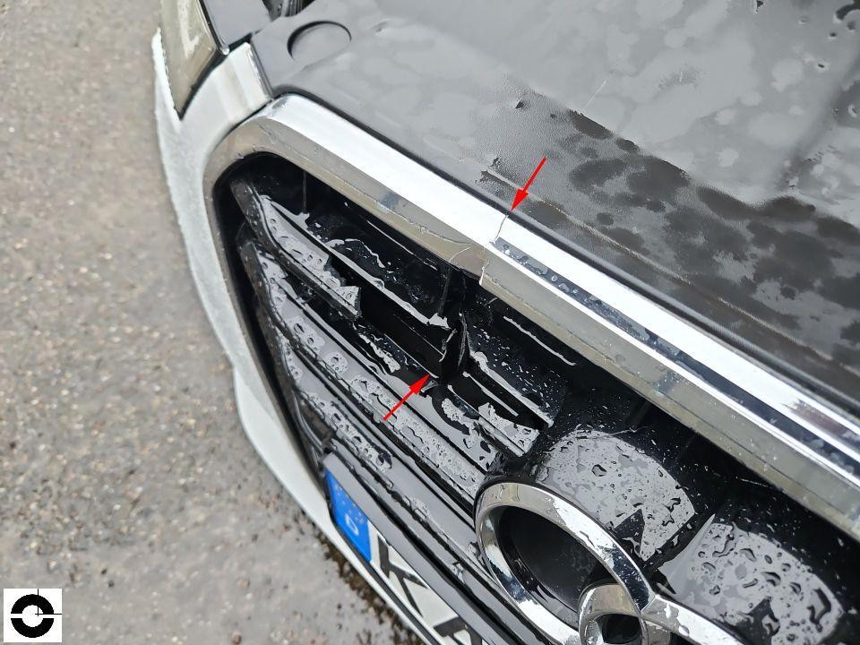 Frontbereich mit Kühlergrill, rote Pfeile markieren Kratzer an Chromleiste und Grill