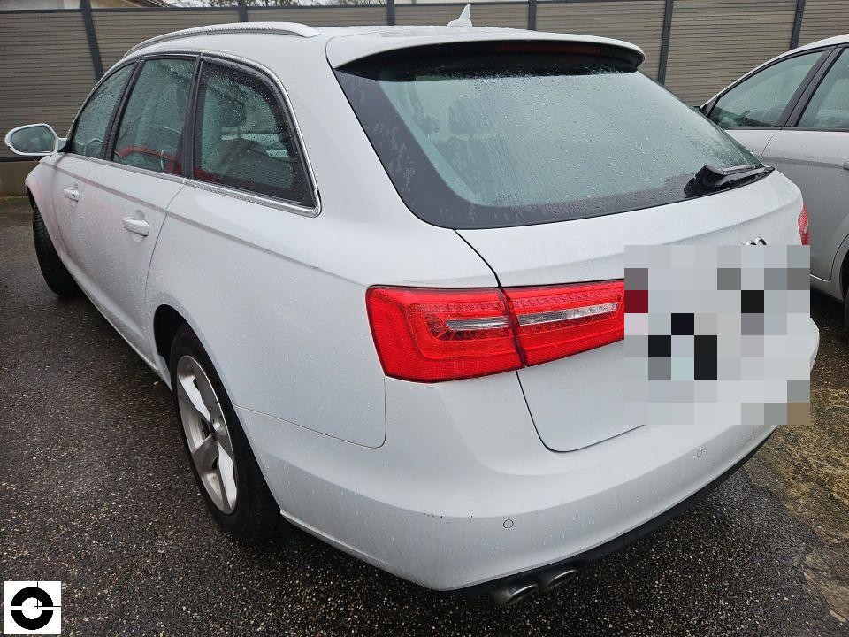 Heckansicht schräg links, weißer Kombi, Kennzeichen pixeliert, nasser Parkplatz