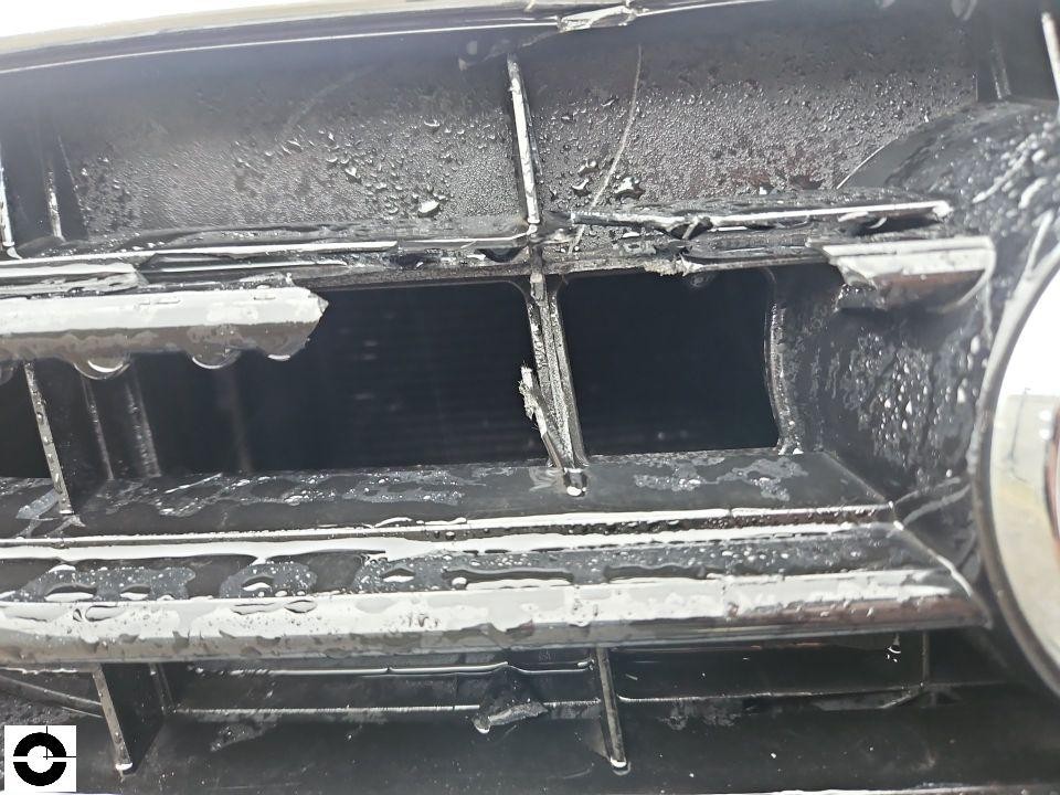 Nahaufnahme beschädigter Kühlergrill, Chromleisten verbogen und gebrochen, nass