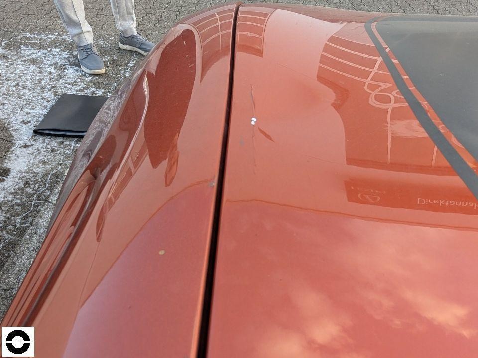 Fahrzeugdach von oben, roter/kupferfarbener Lack mit leichten Kratzern und Spiegelungen