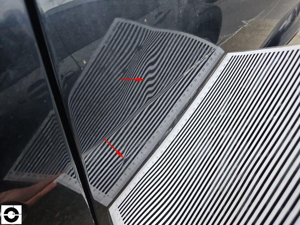 Dellenanalyse mit Streifenlichtfolie an dunkler Karosserie, zwei Dellen mit roten Pfeilen markiert