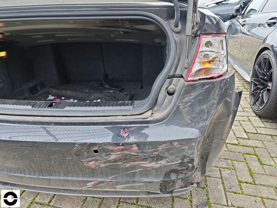 Heckansicht mit geöffnetem Kofferraum, starke Kratzer und Schürfschäden an Heckstoßstange rechts