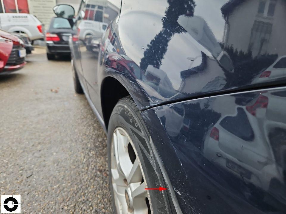 Hinterer linker Kotflügel mit Kratzern und Lackschäden, roter Pfeil markiert Schadenstelle