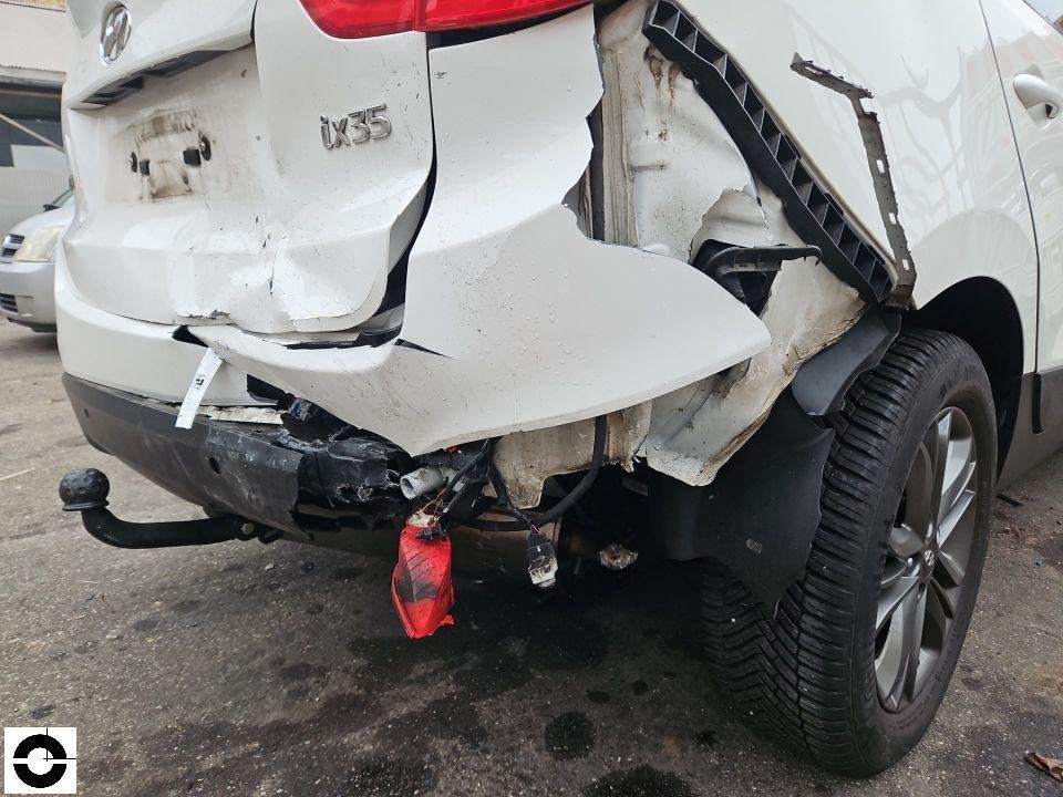 Schwerer Heckschaden links, Stoßstange abgerissen, Rückleuchte hängt lose, Anhängerkupplung sichtbar