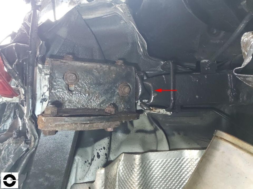 Unterboden-Ansicht, Getriebe/Motor-Bereich mit rotem Pfeil auf Beschädigung, Ölspuren sichtbar