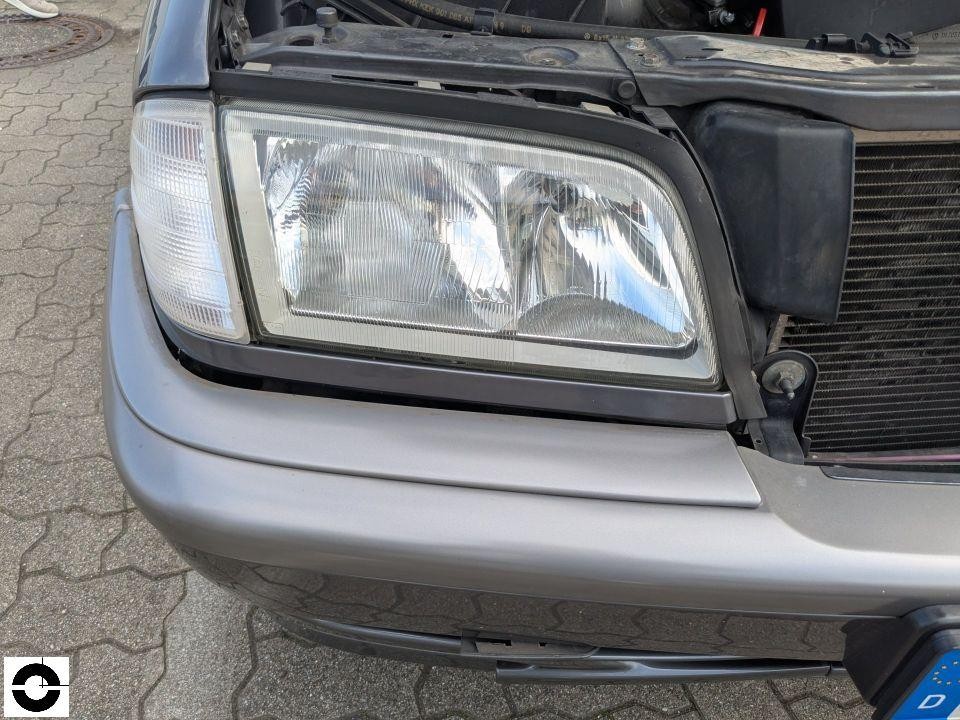 Frontscheinwerfer links bei geöffneter Motorhaube, Kühler sichtbar, silberne Stoßstange