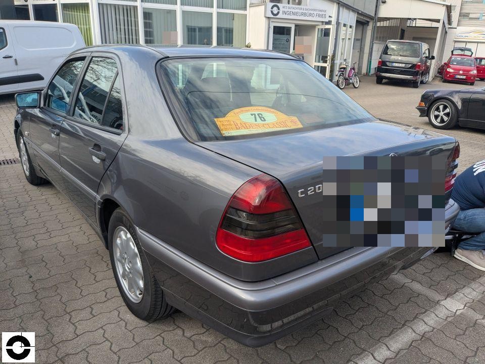 Heckansicht schräg links, graue Limousine mit Rallye-Aufkleber, Kennzeichen pixeliert