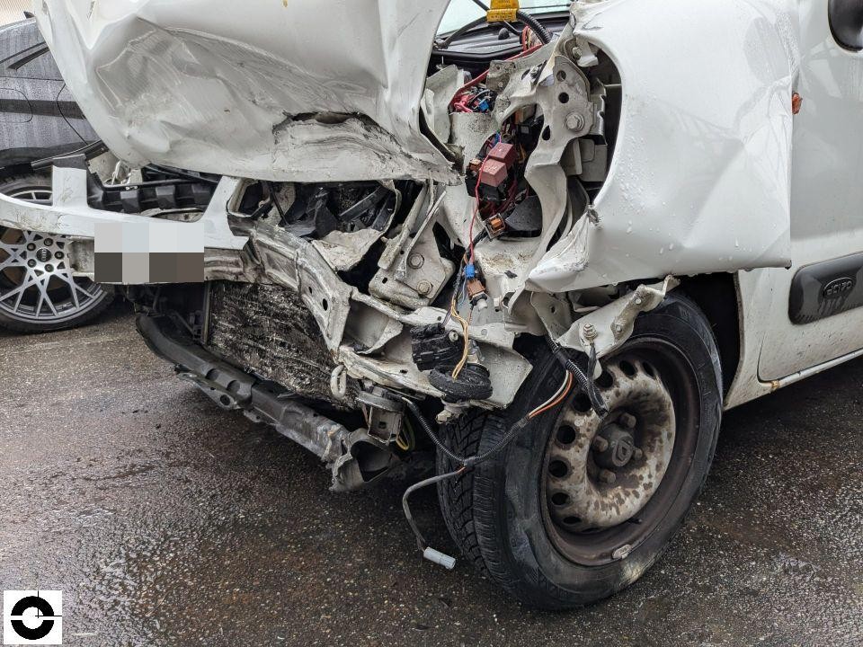 Schwerer Frontschaden links, Kotflügel und Stoßstange massiv deformiert, Kabel freiliegend