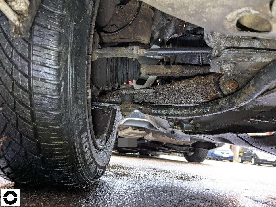 Unterbodenansicht mit Vorderachse, Querlenker, Antriebswelle und Ganzjahresreifen sichtbar