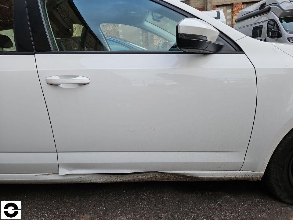 Linke Fahrzeugseite, Fahrertür mit Schaden am unteren Türbereich, abgelöste Lackierung