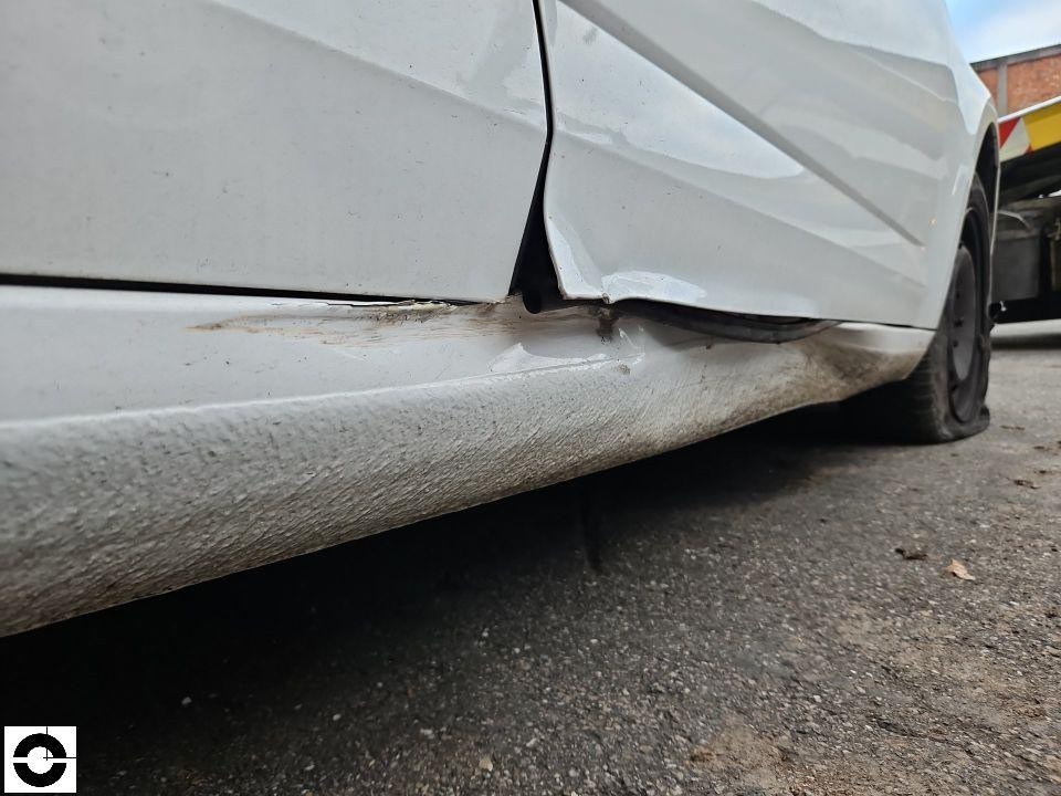 Seitlicher Blick auf beschädigte hintere linke Tür und Schweller, starke Verformungen und Kratzer