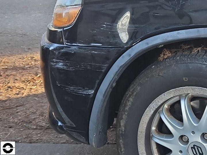 Vorderer linker Kotflügel und Stoßstange mit Kratzern und Schürfspuren, schwarzer Lack