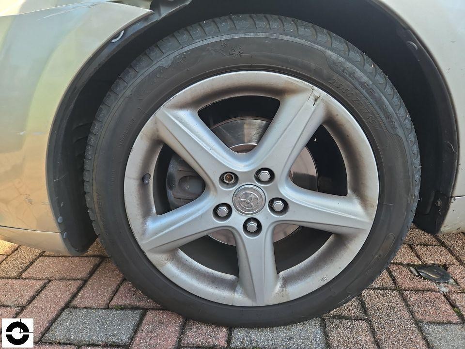 Linkes Vorderrad mit silberner Alufelge, leichte Verschmutzung, Radkasten sichtbar